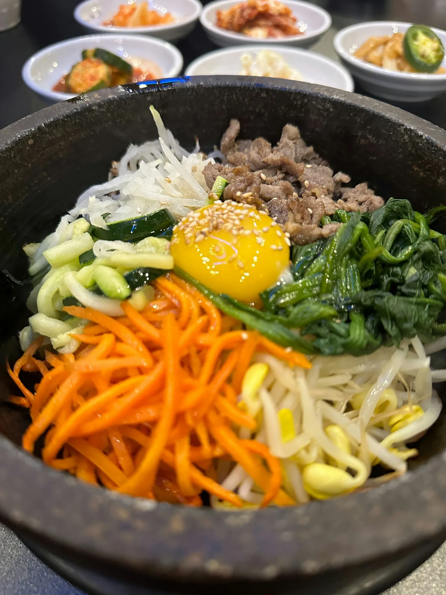 돌솥 위에 당근·콩나물·시금치·달걀노른자를 올린 비빔밥