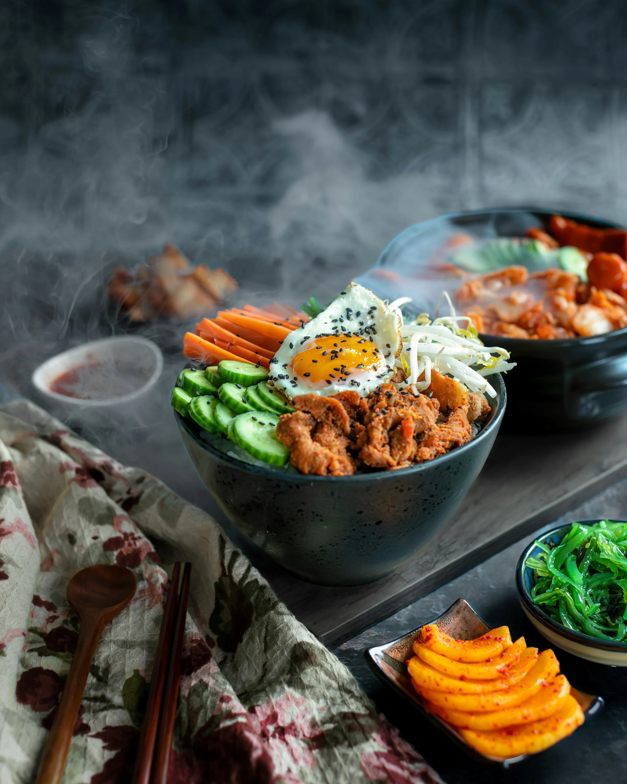어두운 판 위에 놓인 비빔밥 한 그릇과 반찬 그릇들